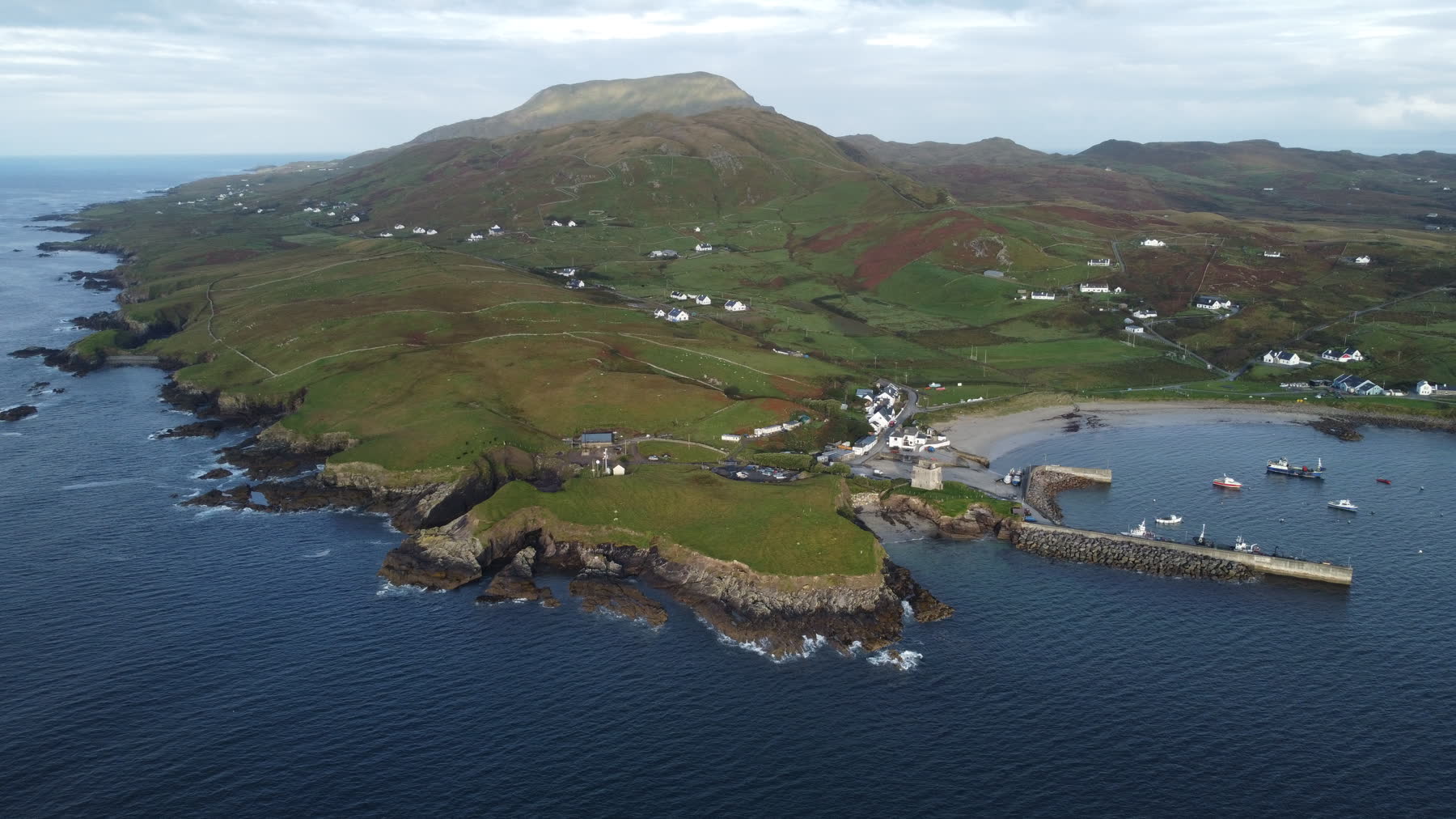 Aerial view of Clare Island harbour, beach, green fields, and the island mountain above Clew Bay