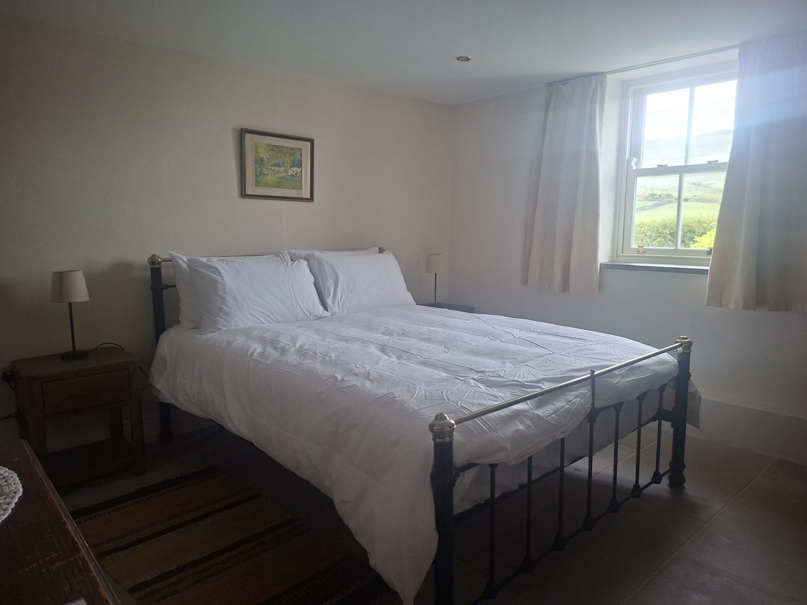Room 2 double guest room with a black metal bed, white bedding, bedside tables, and a window