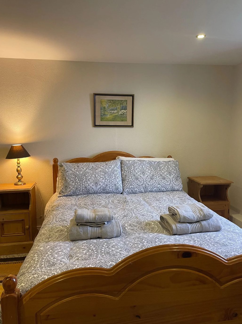 Room 3 double guest room with a timber bed, patterned bedding, bedside tables, folded towels, and warm lighting